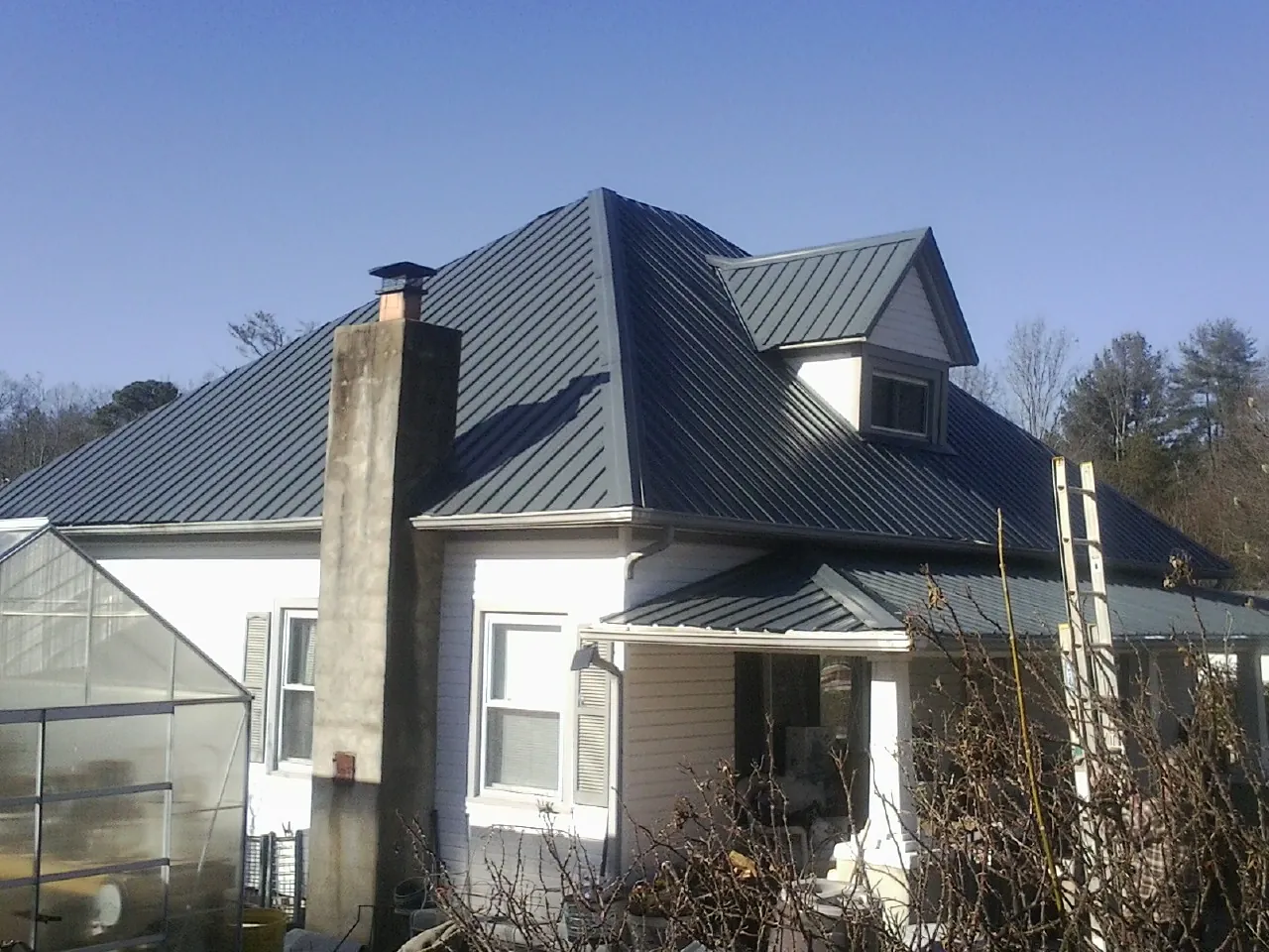 Dark blue standing seam metal roof on a white farmhouse with dormer — Slate & Tile Roof Repair by Roofing Brothers in Attica