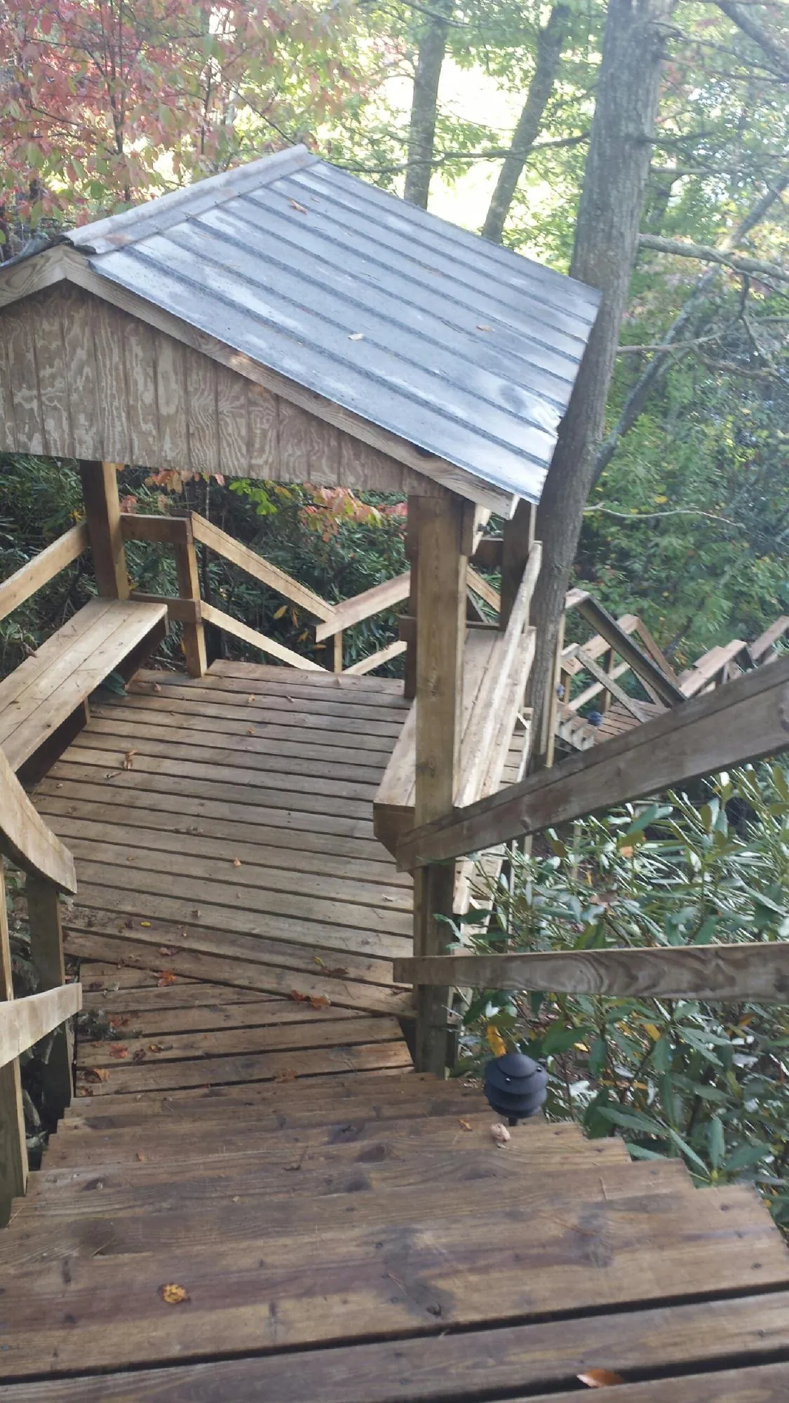 Metal roofed shelter over wooden steps on a wooded walkway — Skylight Repair & Installation work by our crew in Attica